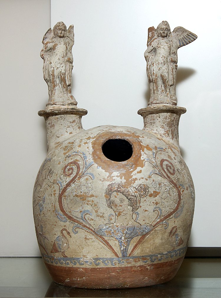 COMPARANDUM: Pottery askos painted with a female head rising up from a flower, with terracotta statuettes of Erotes added above, cr. 310-290BC, Canosa, Apulia, Italy