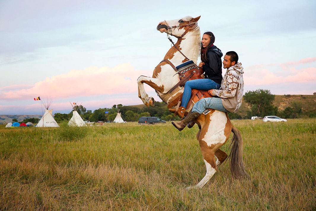 Stevana Salazar rides with Arlo Standing Bear, 26 August 2016, photo by Terray Sylvester, Standing Rock camp, Dakota, U.S.A.